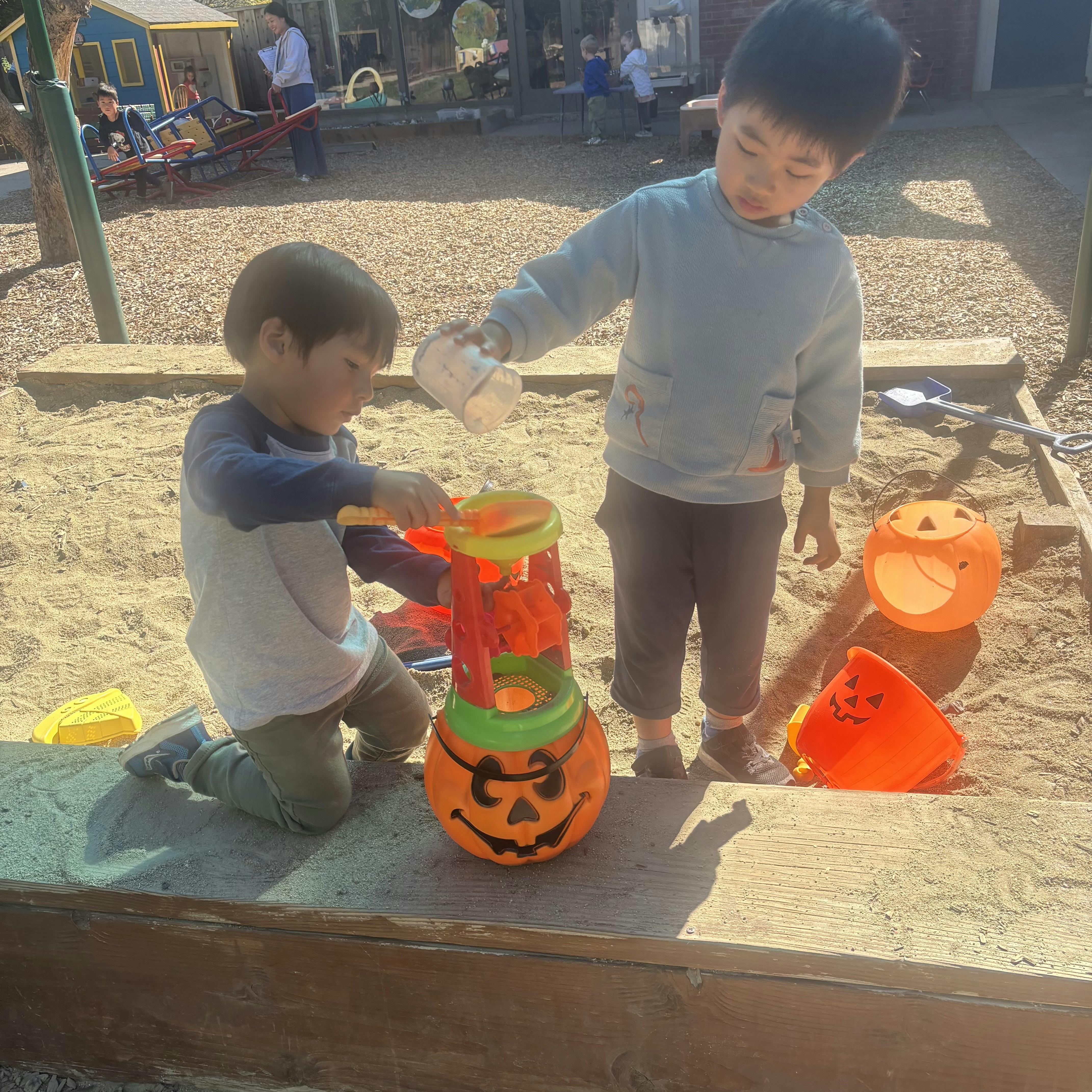 Two children playing with sand toys in a sandbox