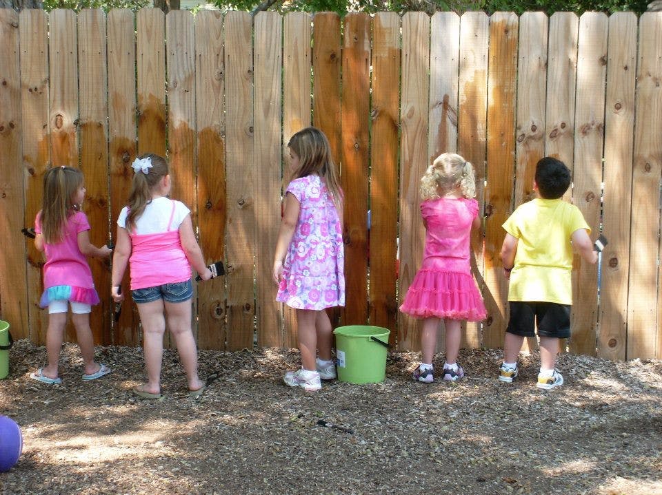 Children painting a wooden fence