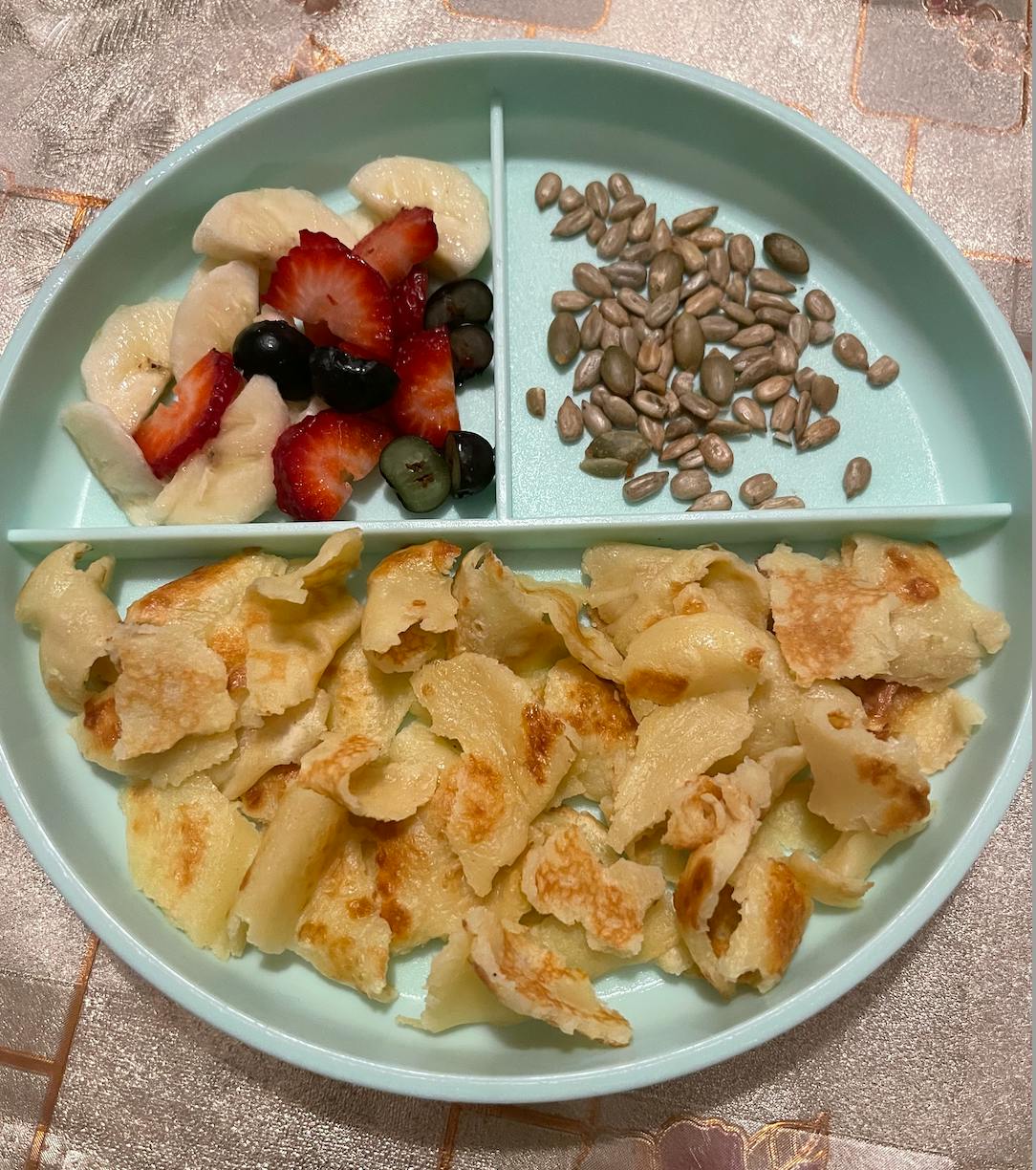Sectioned plate with fruit, seeds, and pancake pieces