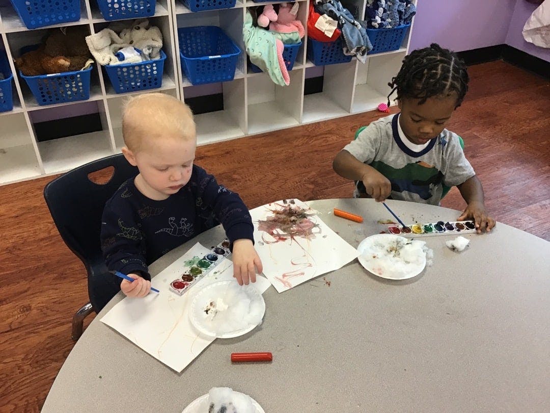 Two children painting at a table in a classroom