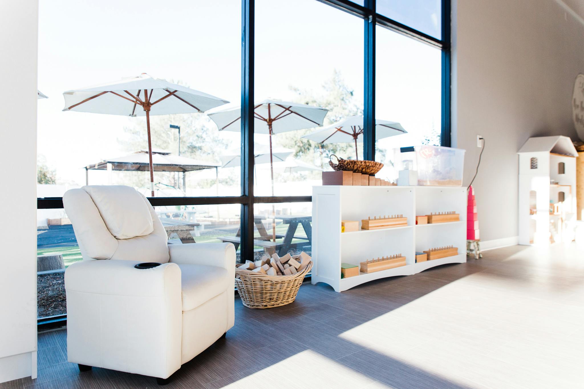 White armchair and shelves with a basket of wood by a large window