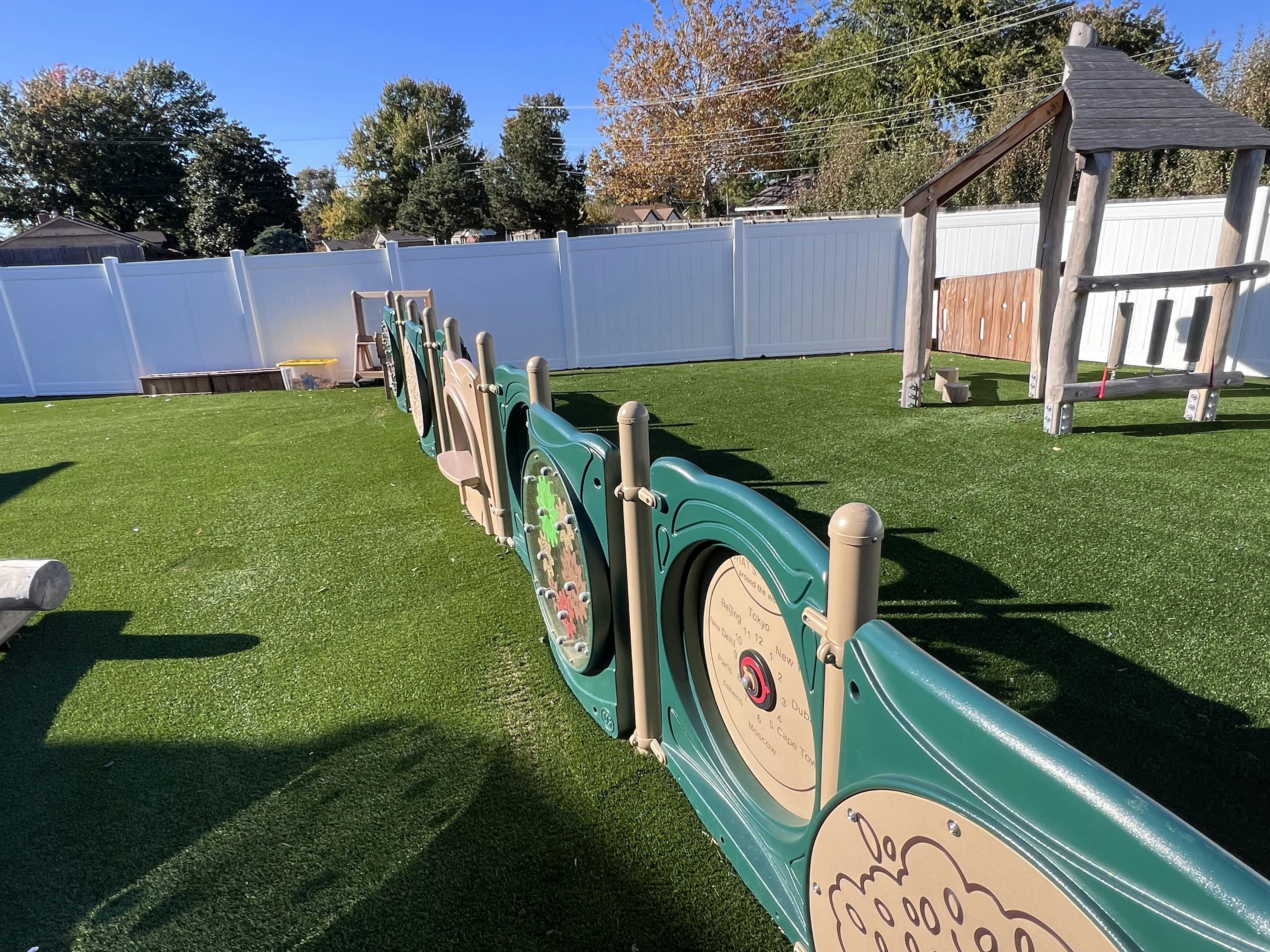 Playground with green artificial turf and a long green activity wall