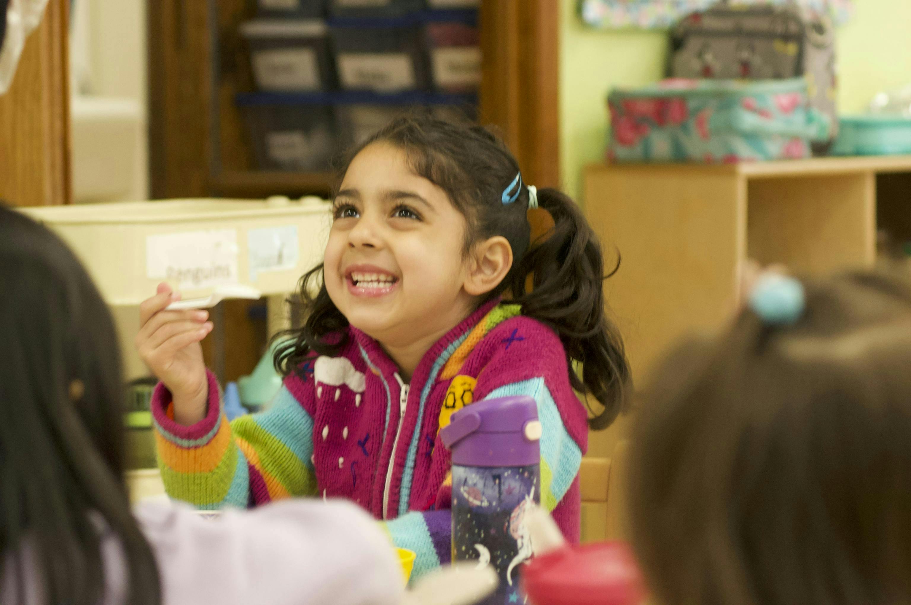 Child in a classroom looking up and smiling