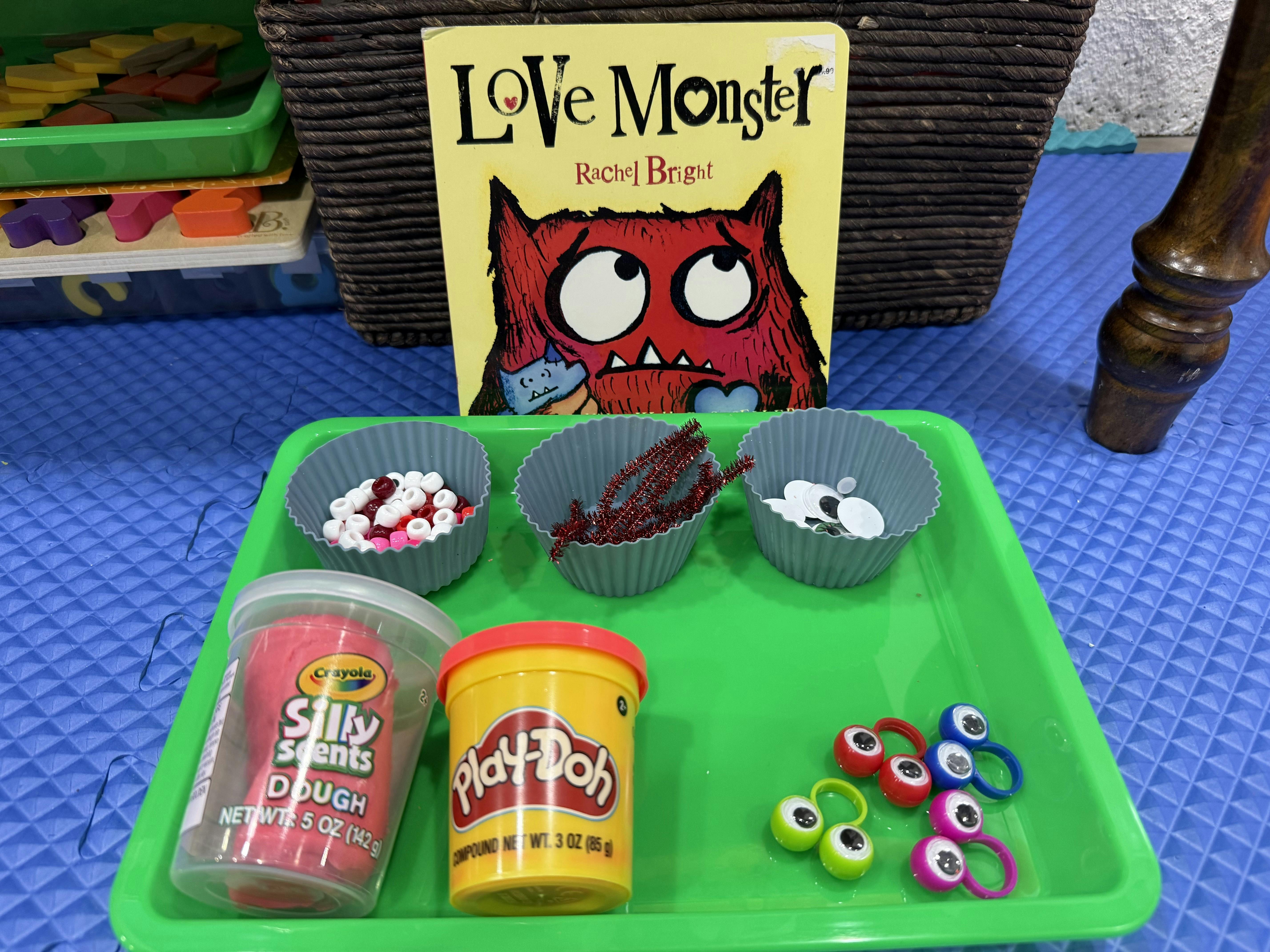Love Monster book next to crafts supplies on a green tray
