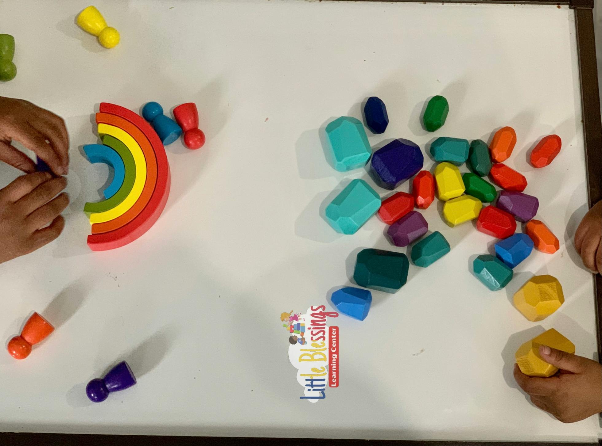 Child playing with colorful wooden blocks and rainbow toy