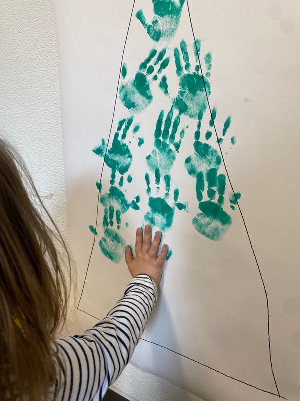 Child making a handprint on a paper with other handprints