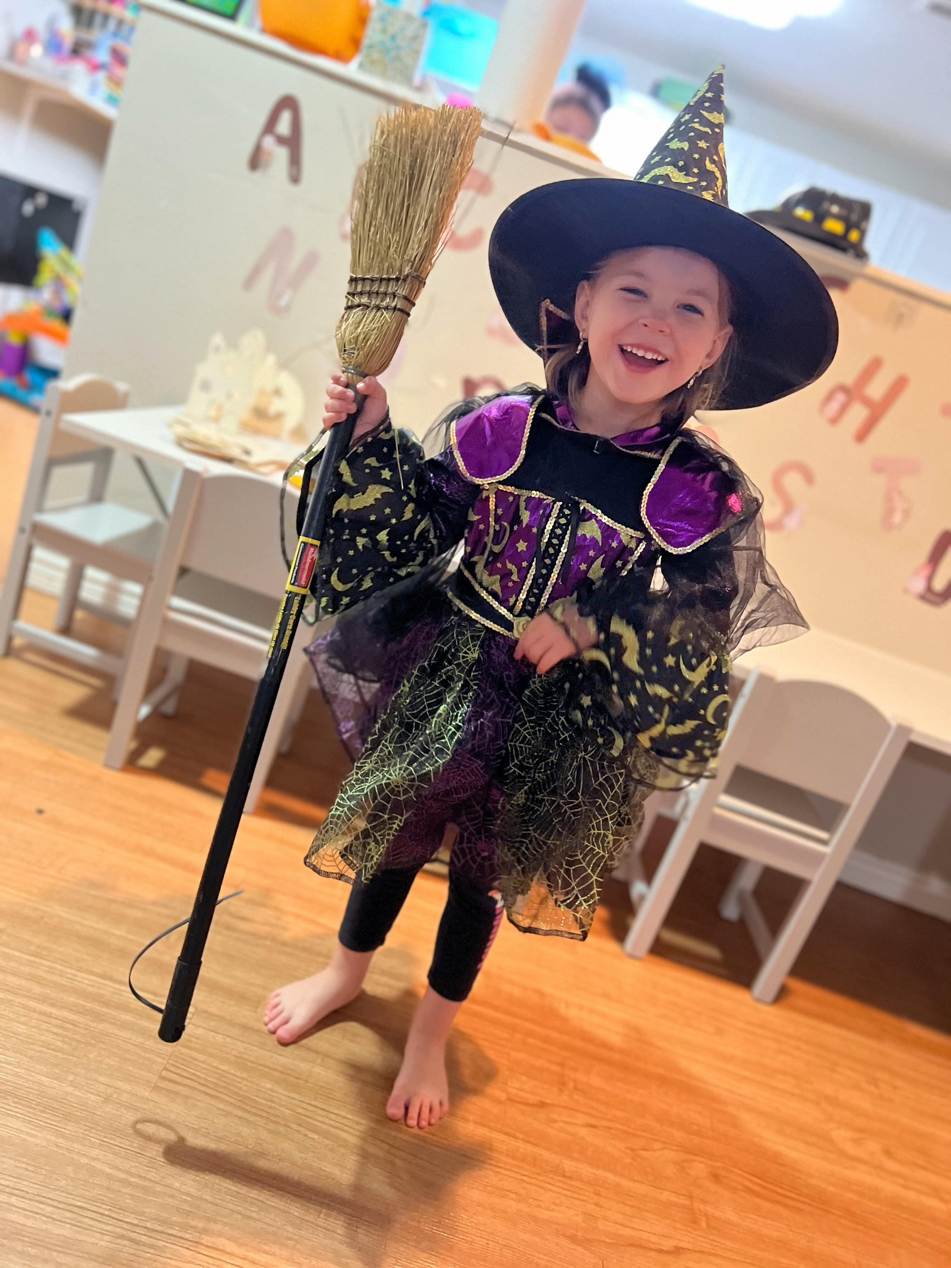 Child in a witch costume holding a broom