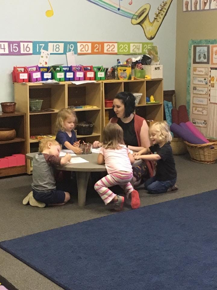 Adult and three children sitting at a table in a classroom