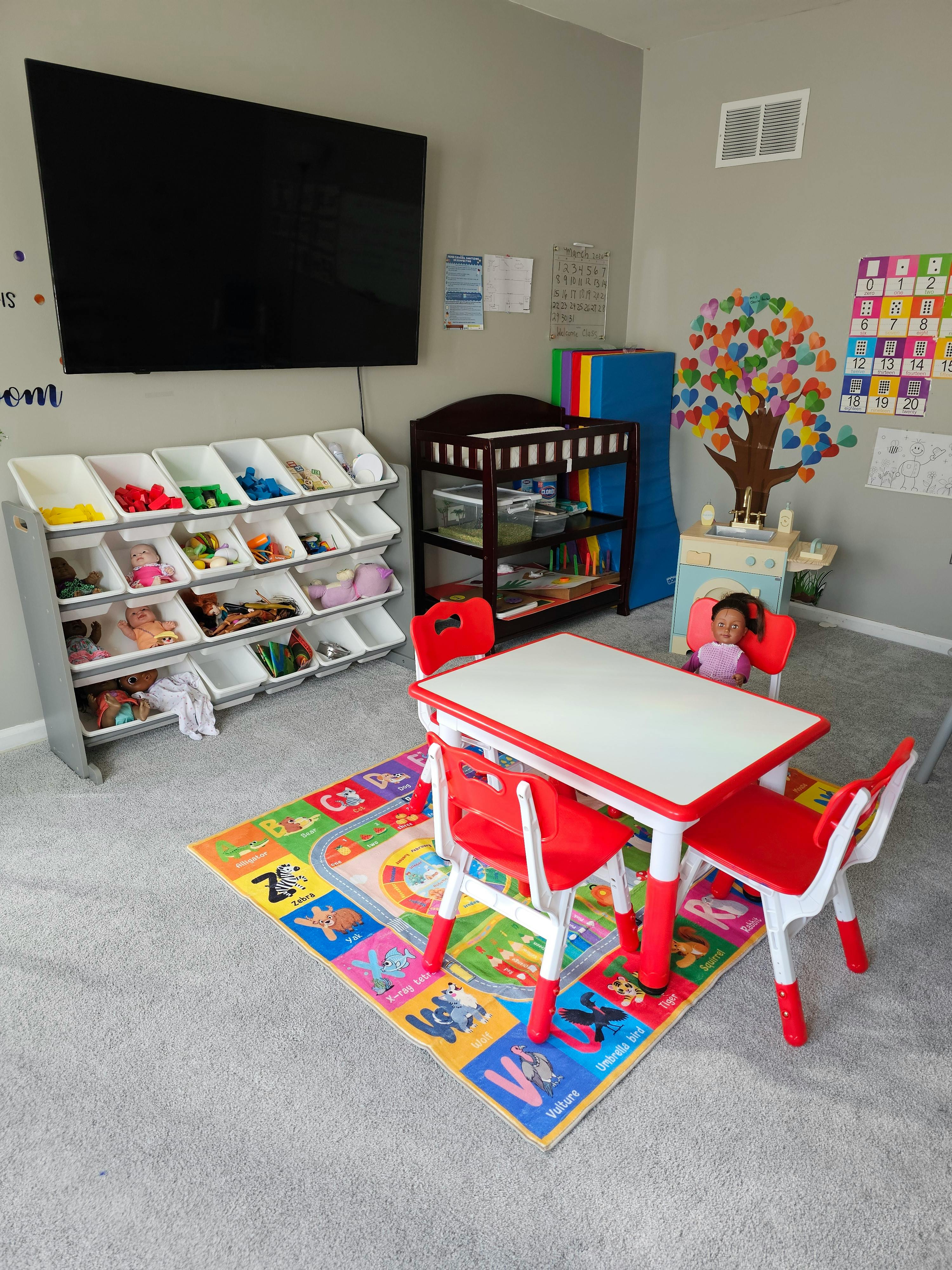 Small table and chairs on a colorful educational rug in a children's play area