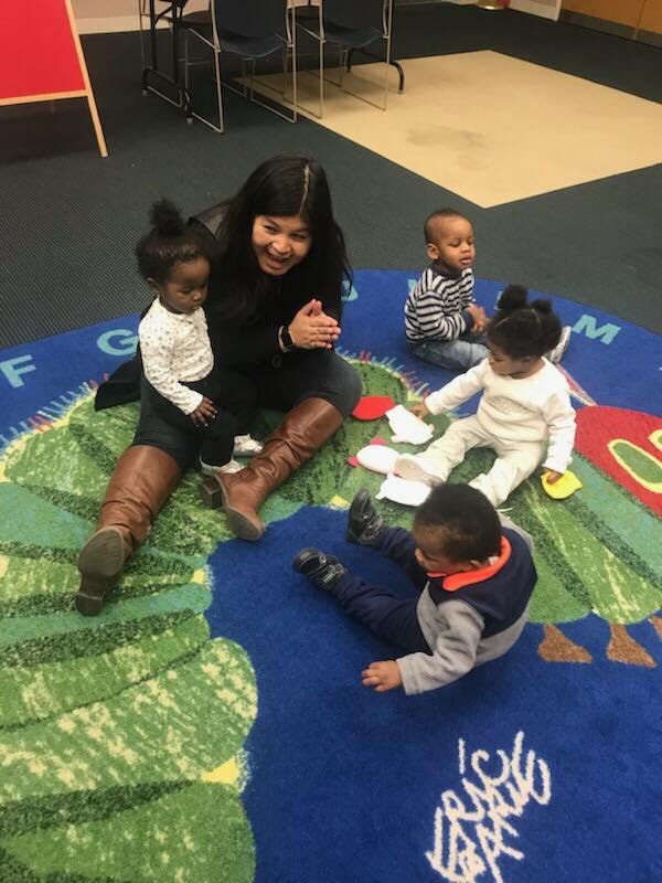 Person sitting on a rug with four children