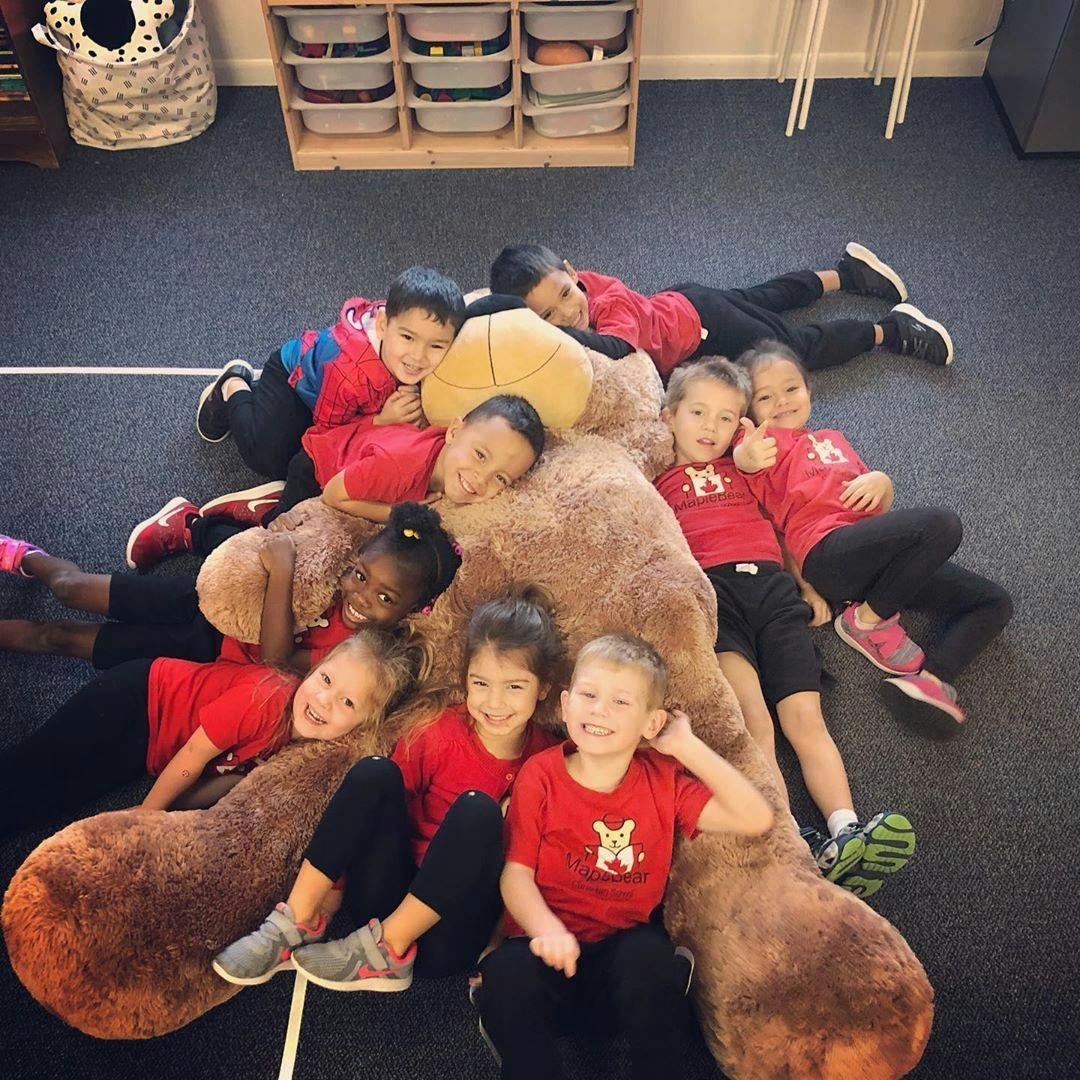 Group of children lying on and around a large stuffed animal