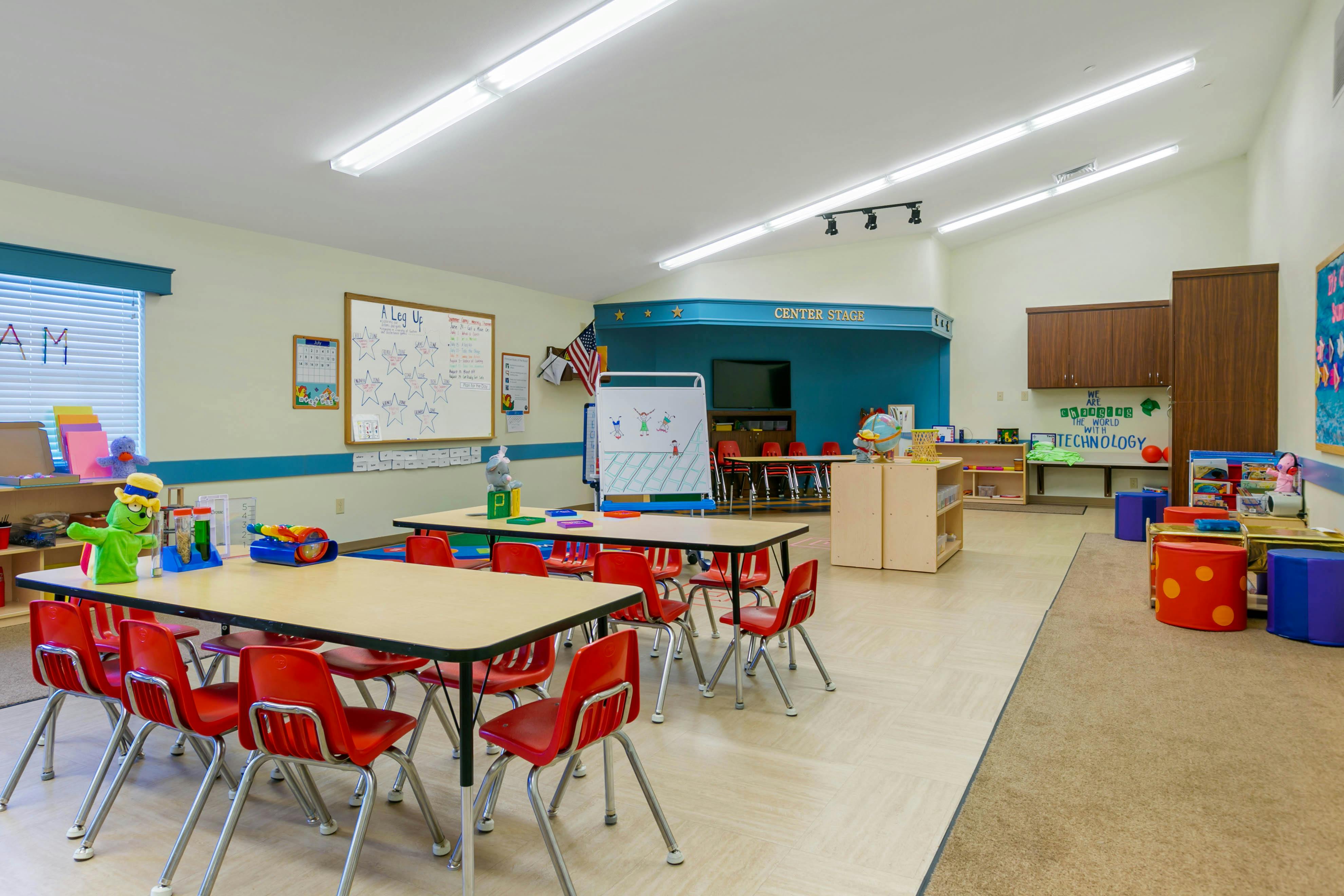 Classroom with child-sized tables and chairs, toys, and a "CENTER STAGE" sign