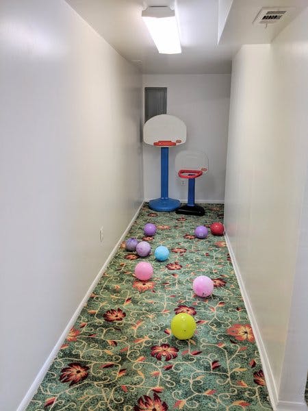 Hallway with a small basketball hoop and multiple colorful balls on the carpet