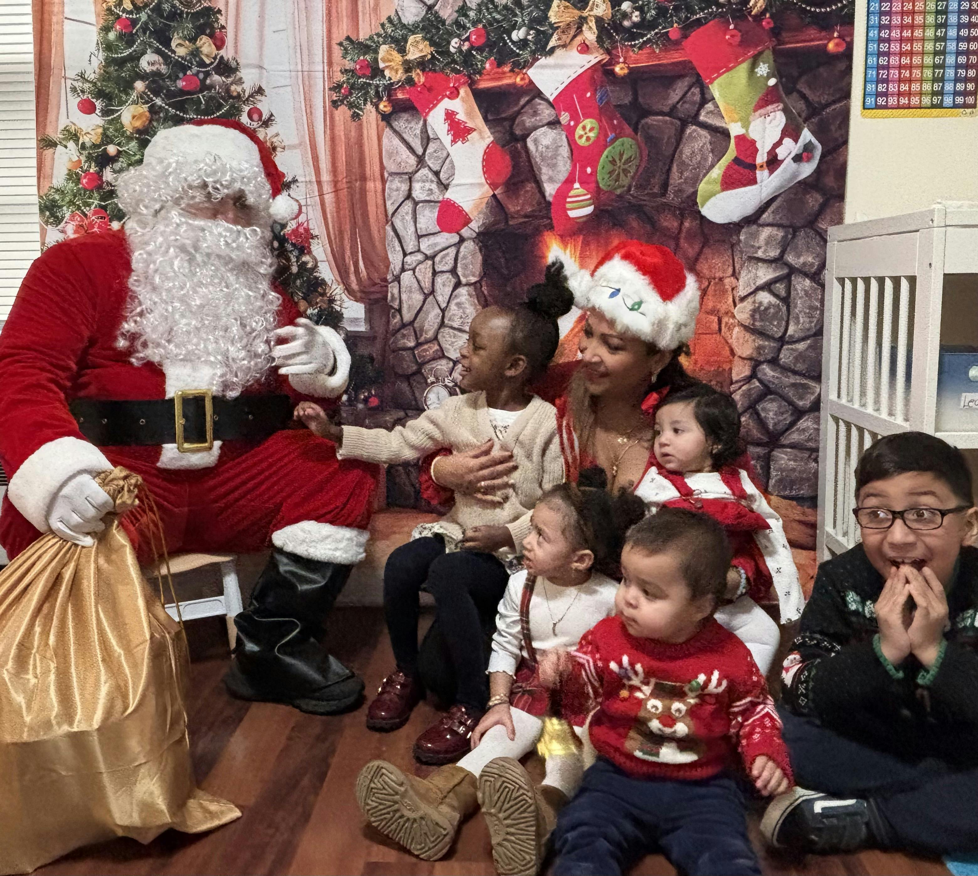 Santa Claus sitting with a woman and several children in a festive setting
