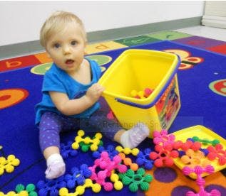 Child playing with colorful building toys and a yellow bucket