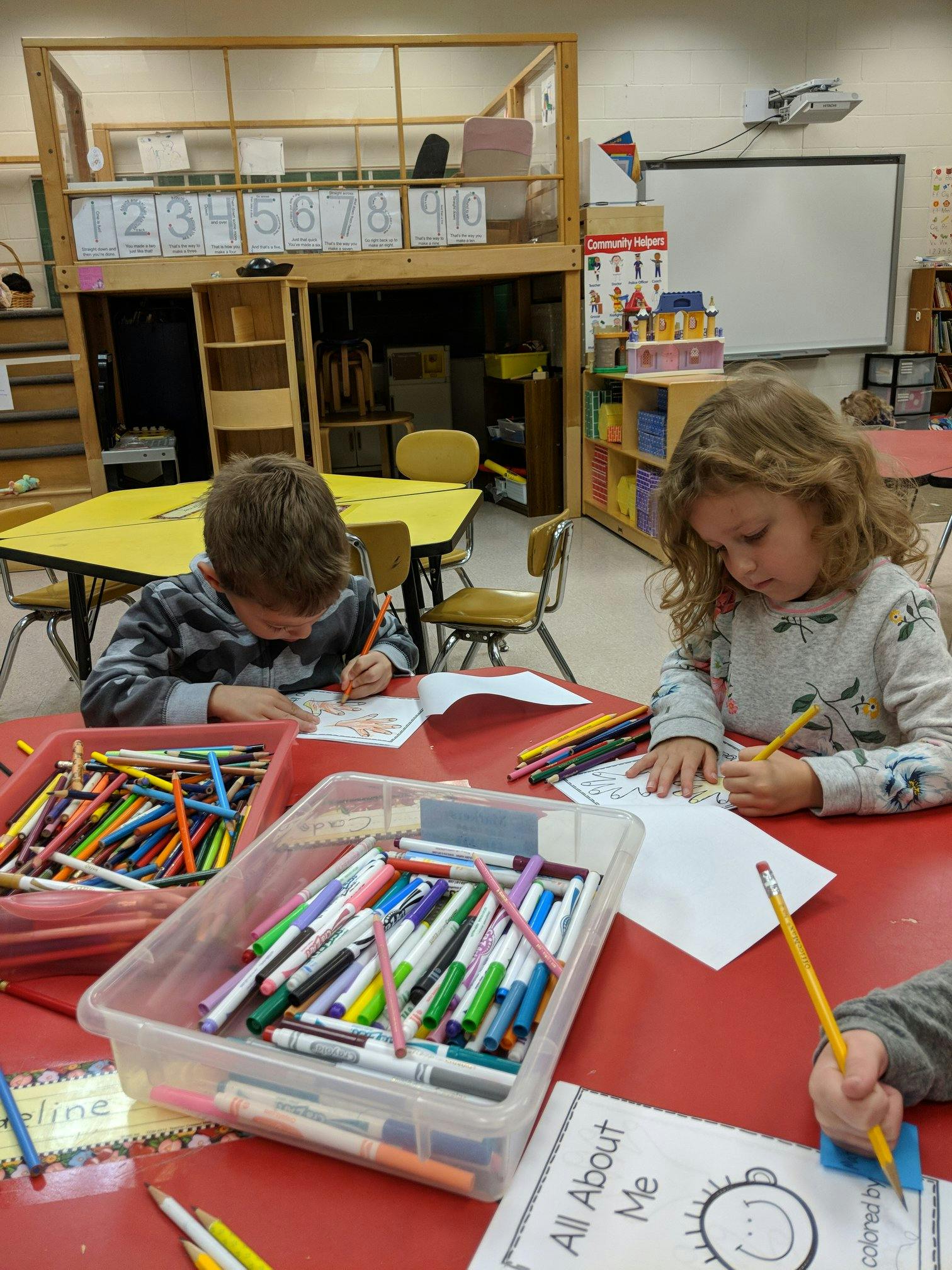 Two children drawing at a table in a classroom