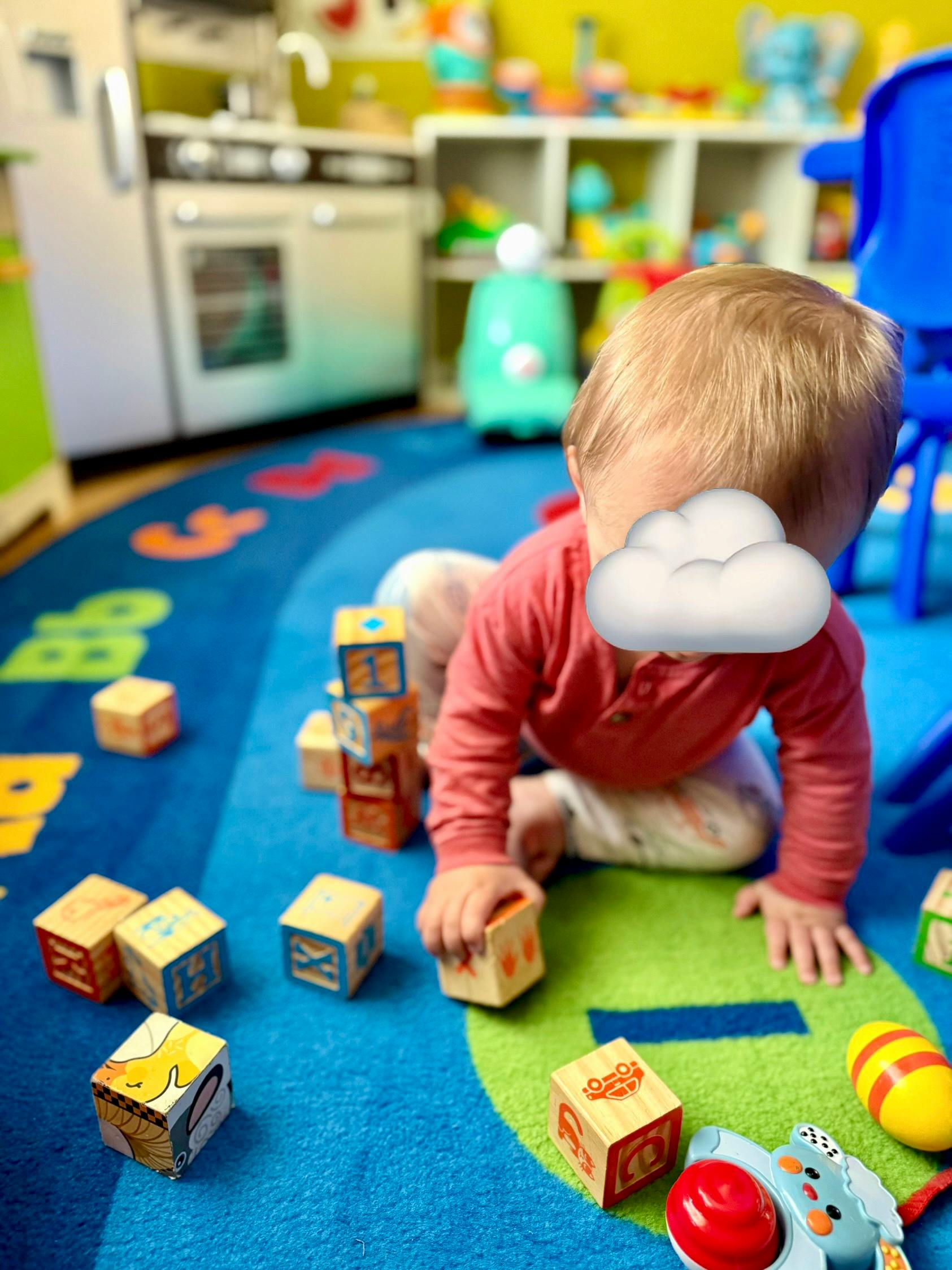 Child playing with wooden blocks on a blue rug