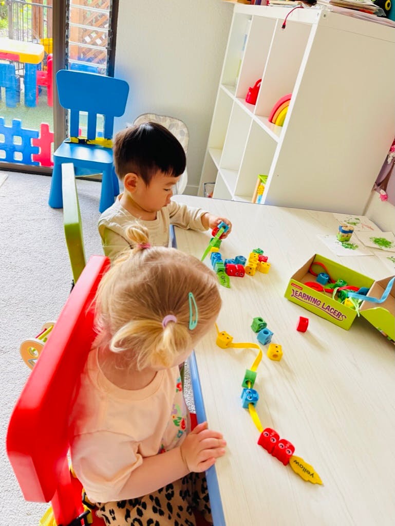 Two children playing with colorful building blocks at a table