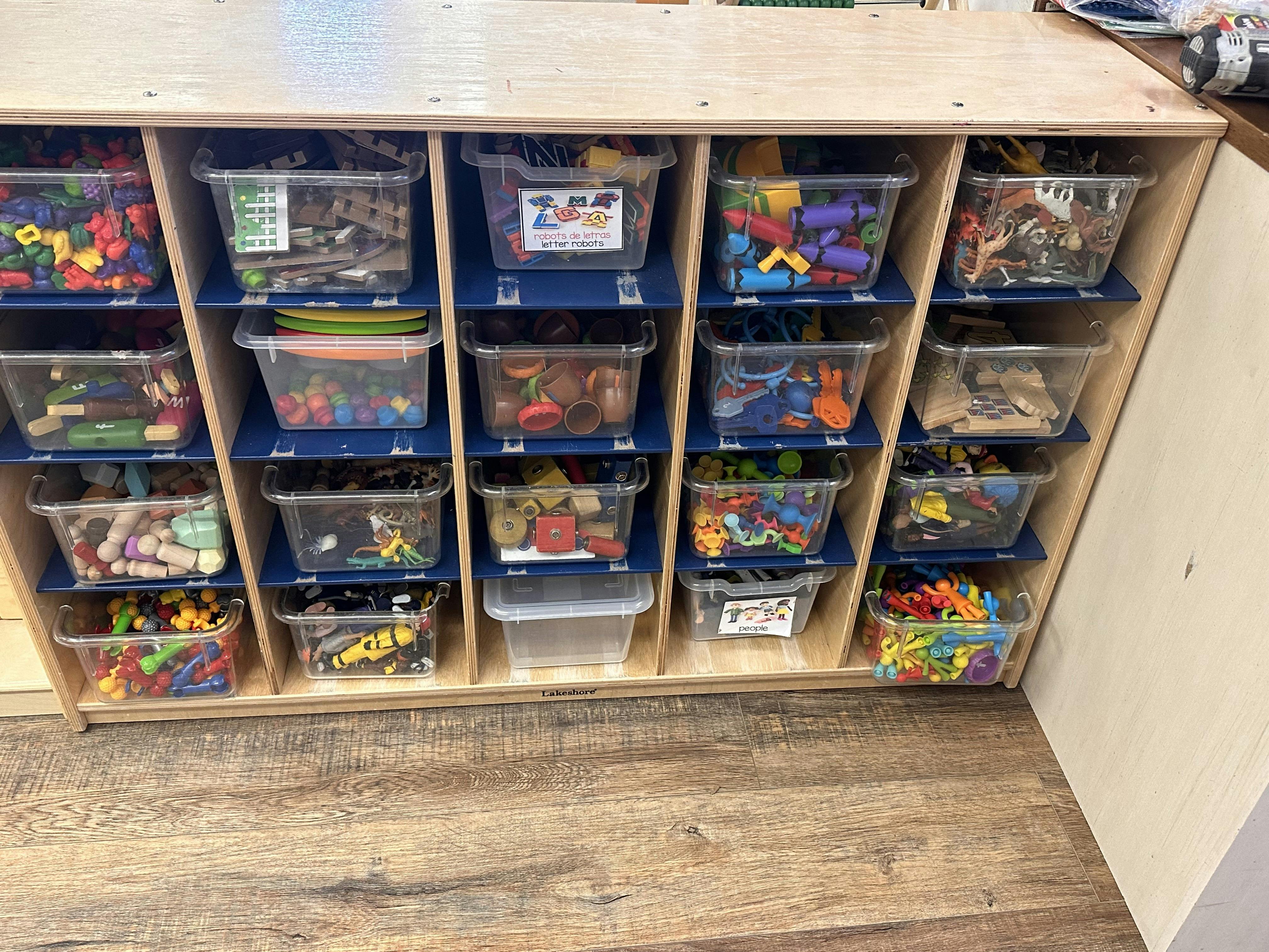 Shelving unit with clear bins filled with various toys and objects