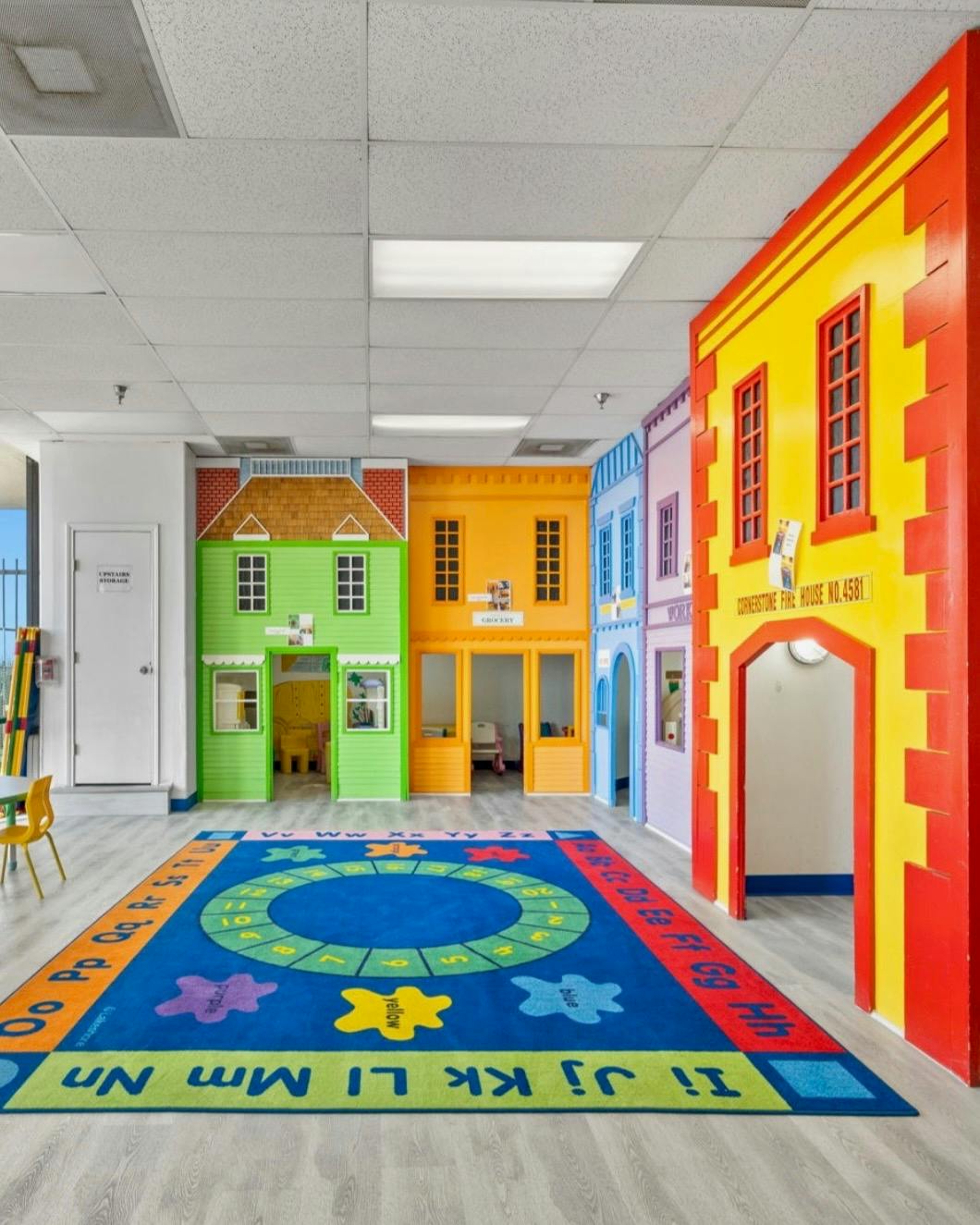 Playroom with colorful building facades and an alphabet rug