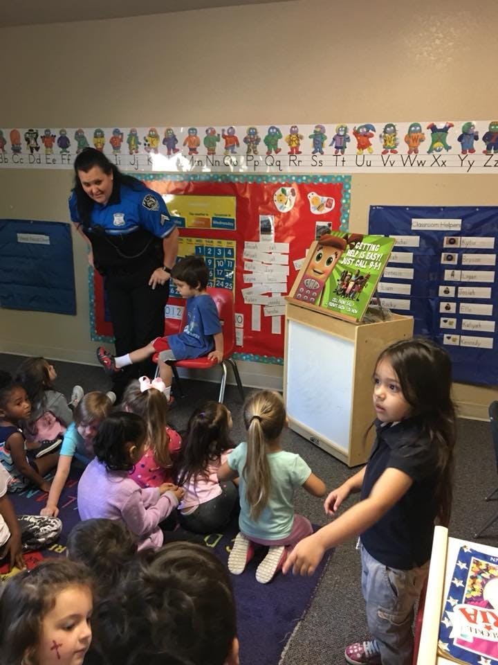Person in uniform speaking to children in a classroom