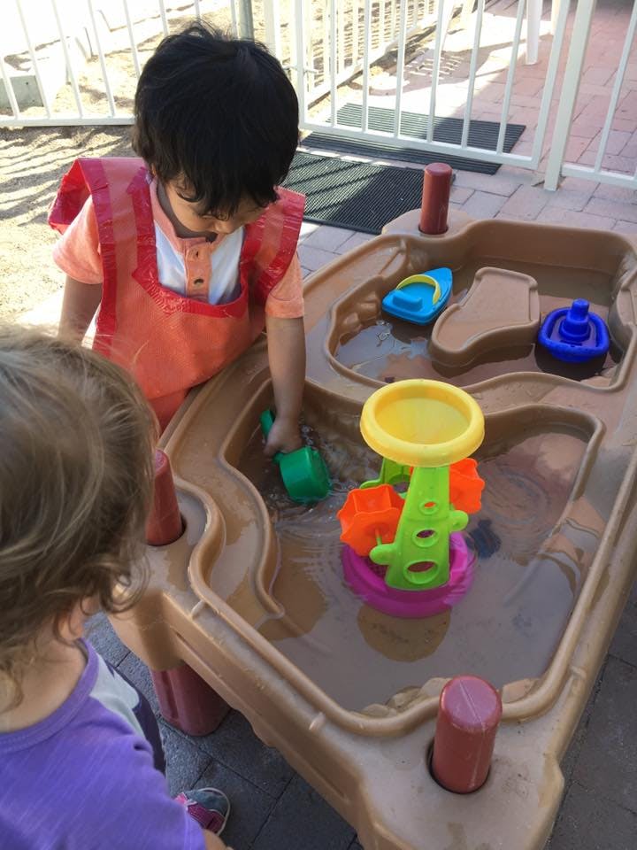 Two children playing with a water table