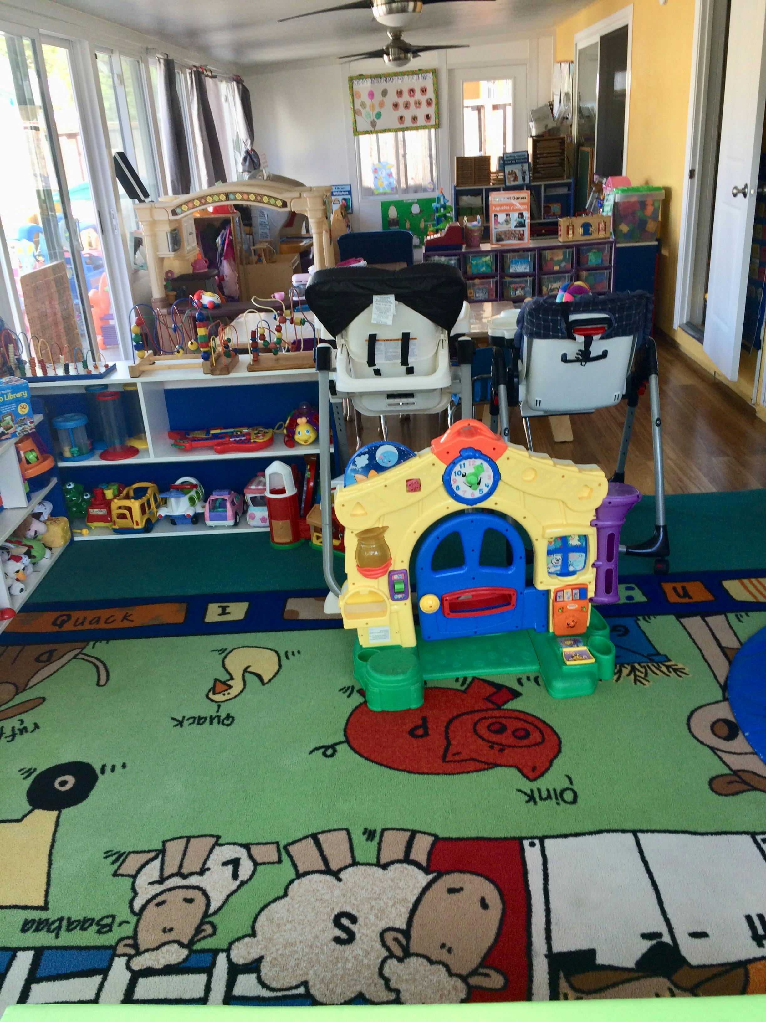 Playroom with a colorful rug, toys, and high chairs