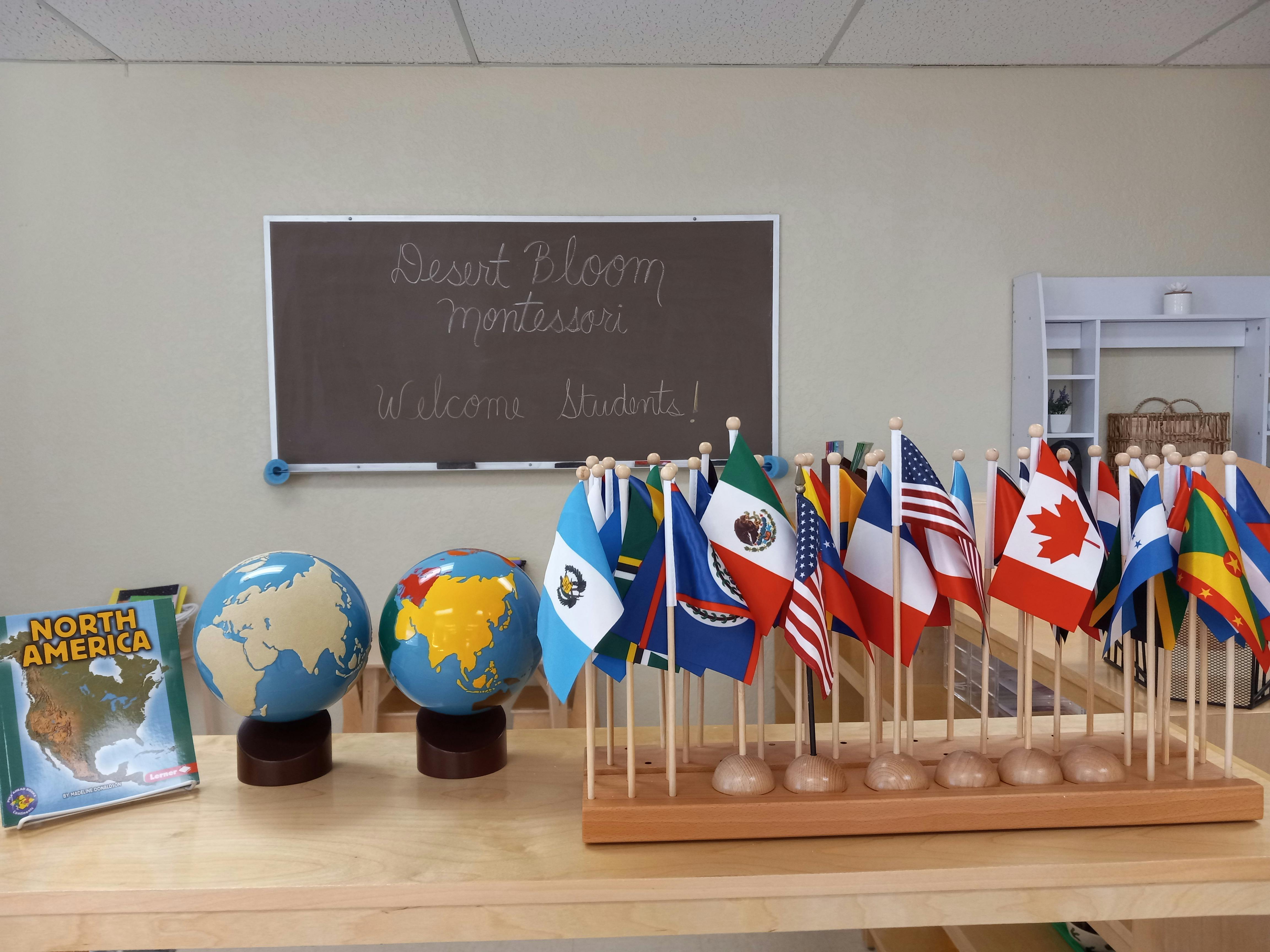 Two globes and a collection of international flags on a table in a classroom