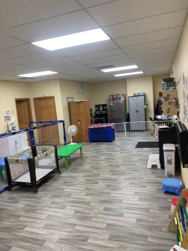 Room with a crib, green table, and white safety gate