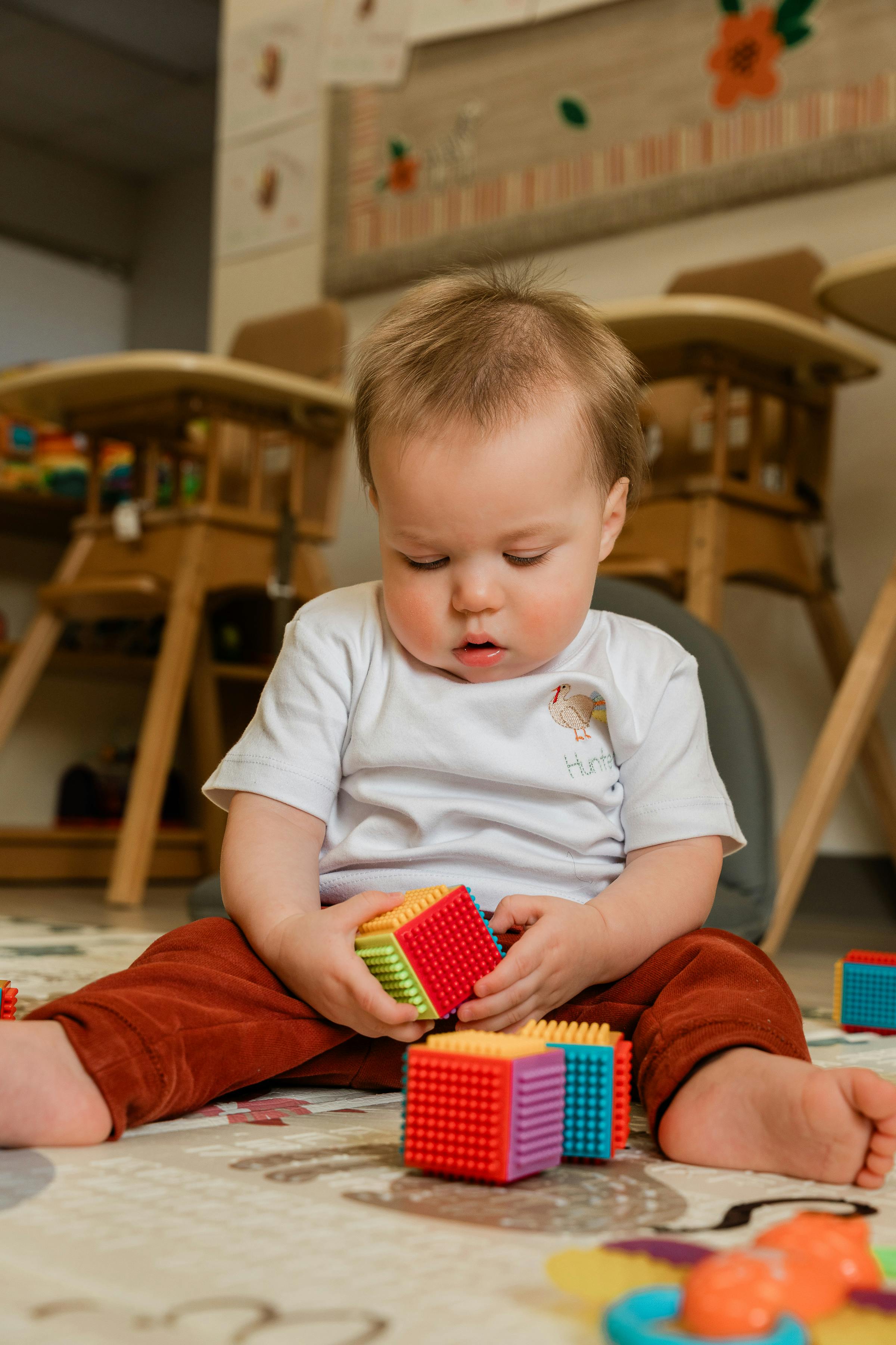 Child sitting on floor playing with colorful interlocking blocks