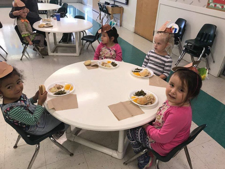 Four children sitting at a round table with plates of food