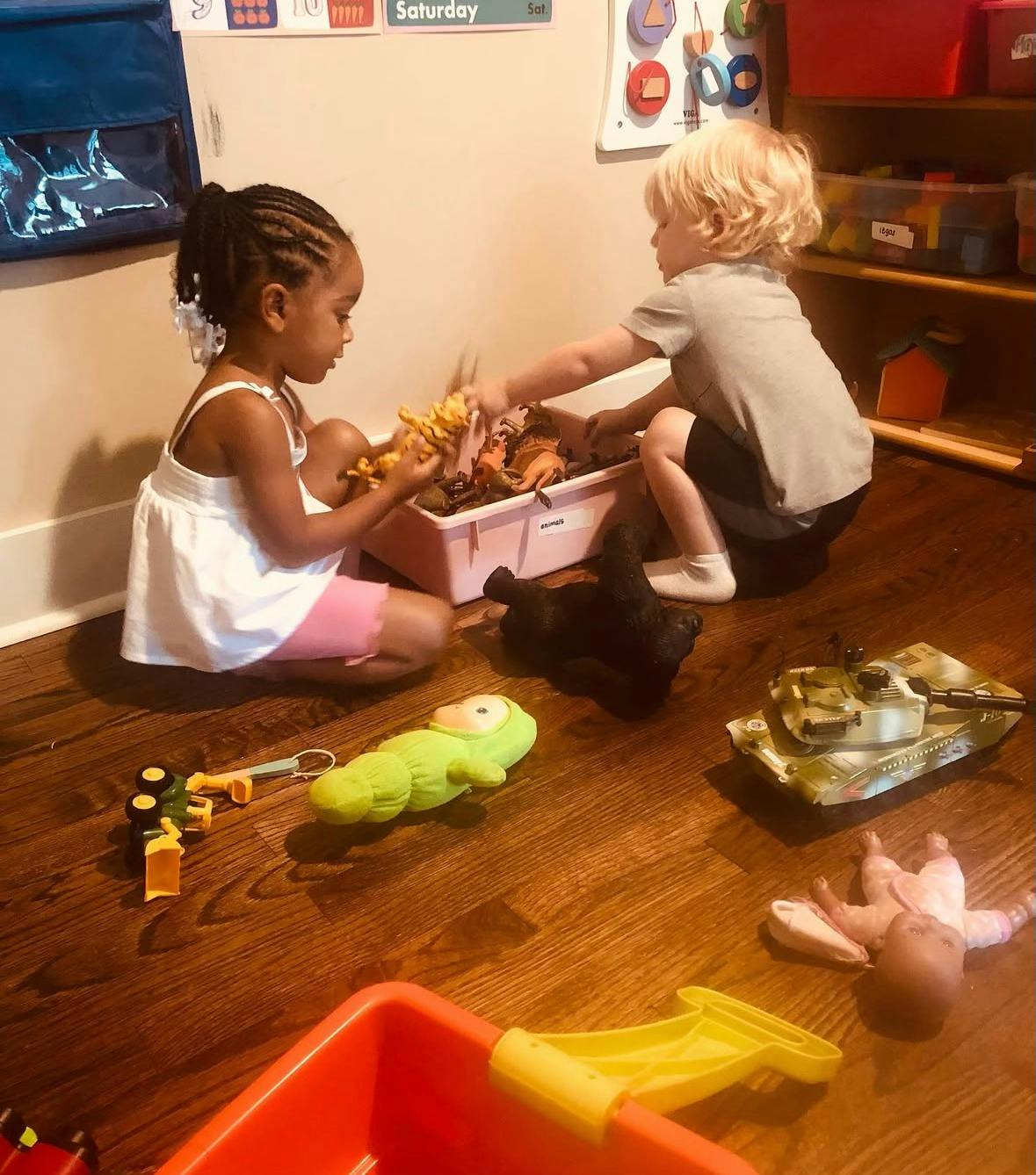 Two children playing with toys on a wooden floor