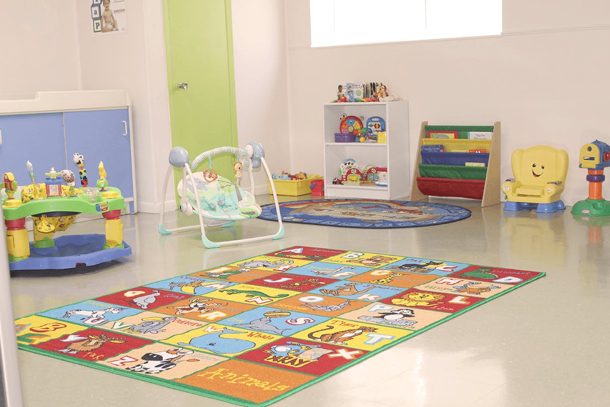 Playroom with colorful alphabet rug, baby swing, and toys