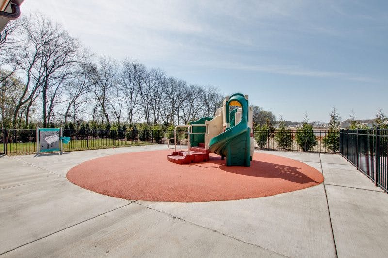 Playground with a slide and climbing structure on a red padded surface