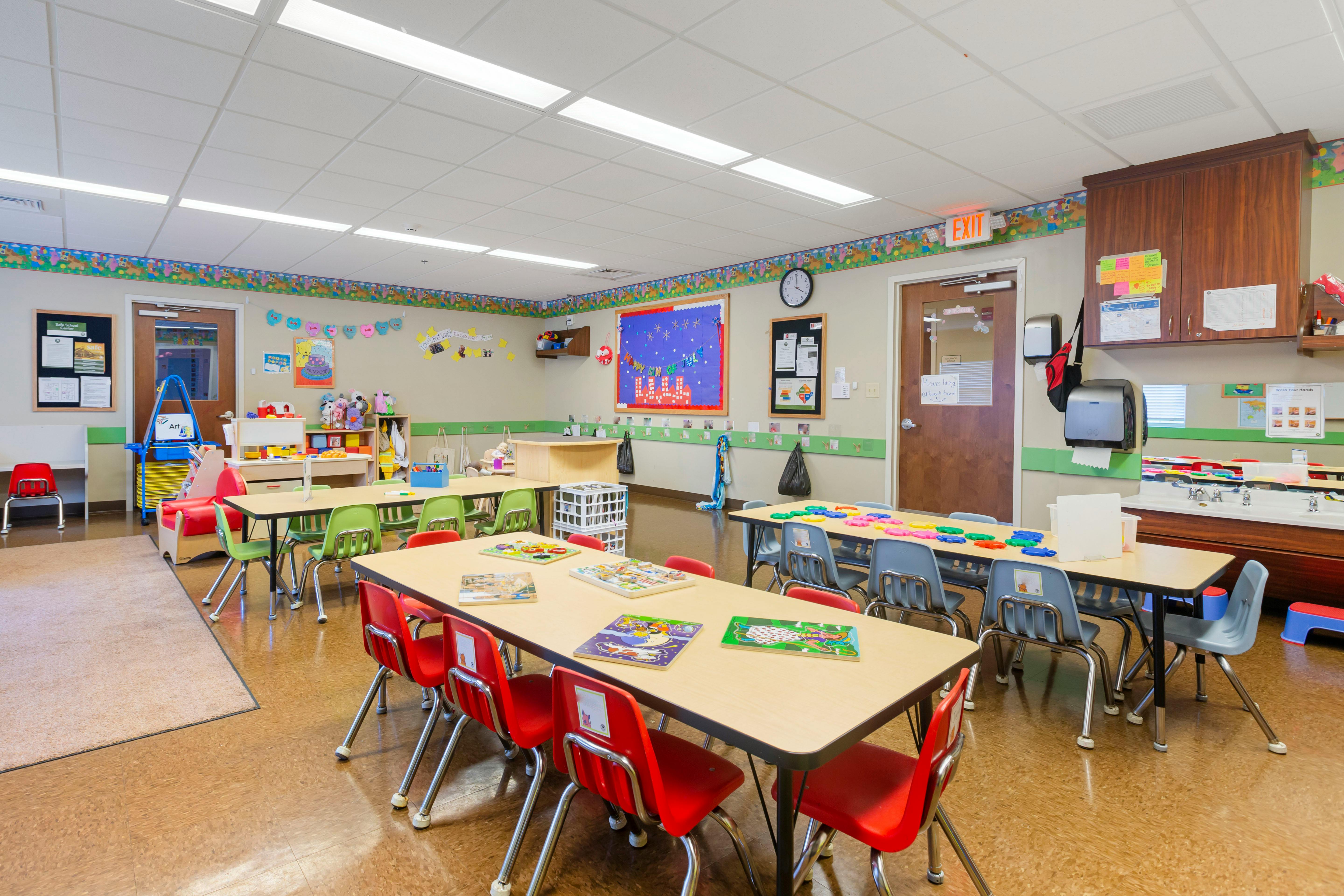 An empty preschool classroom with tables and chairs