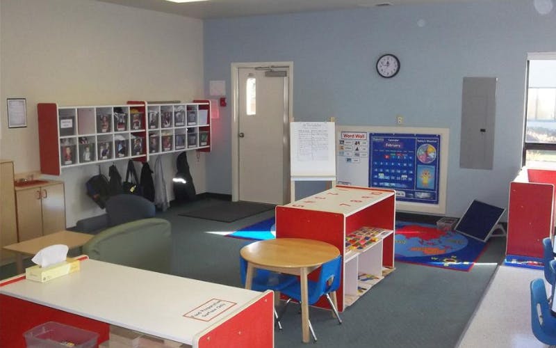 Classroom with cubbies, small tables, and a calendar board