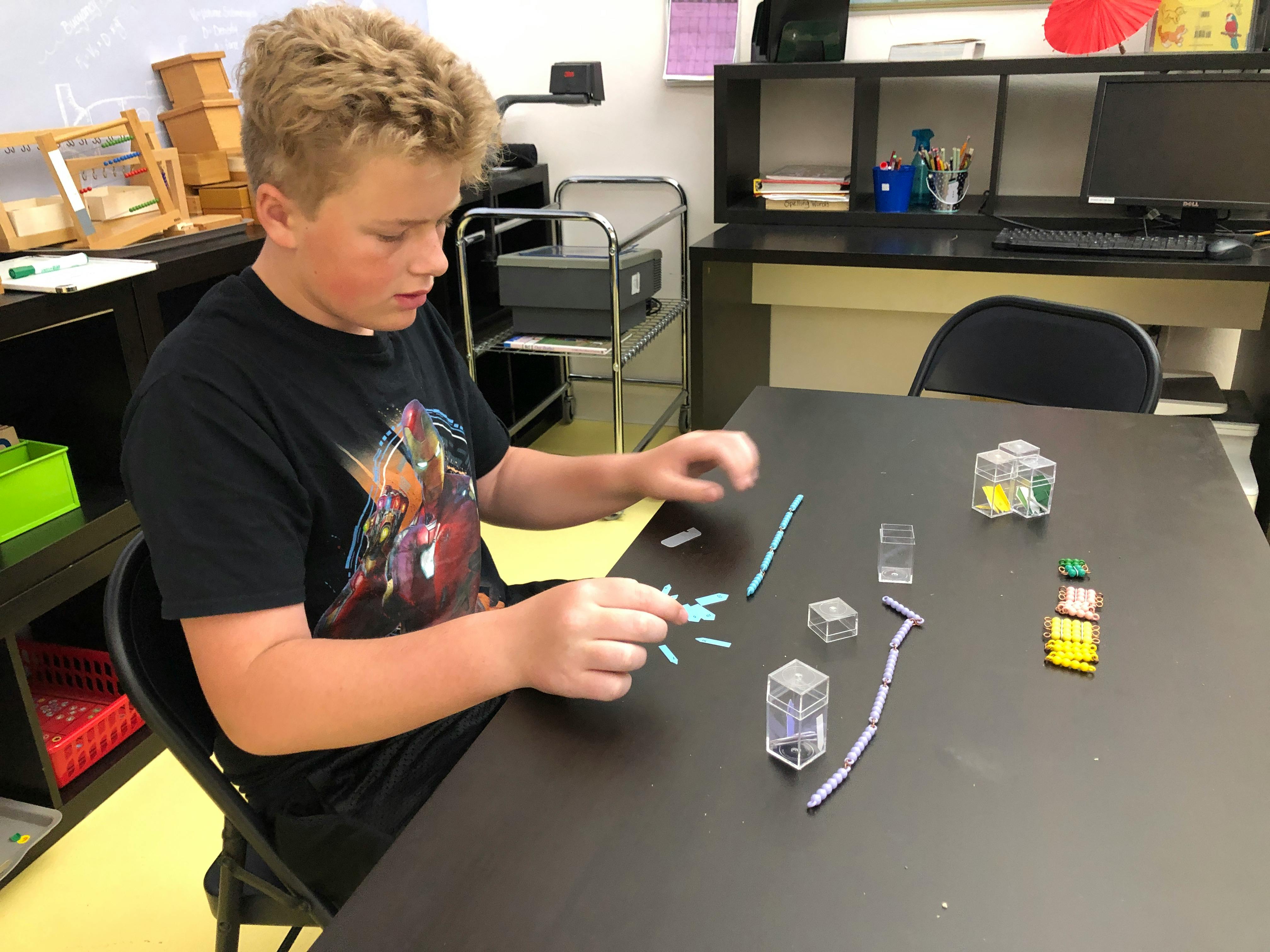 Child sitting at a table manipulating small objects
