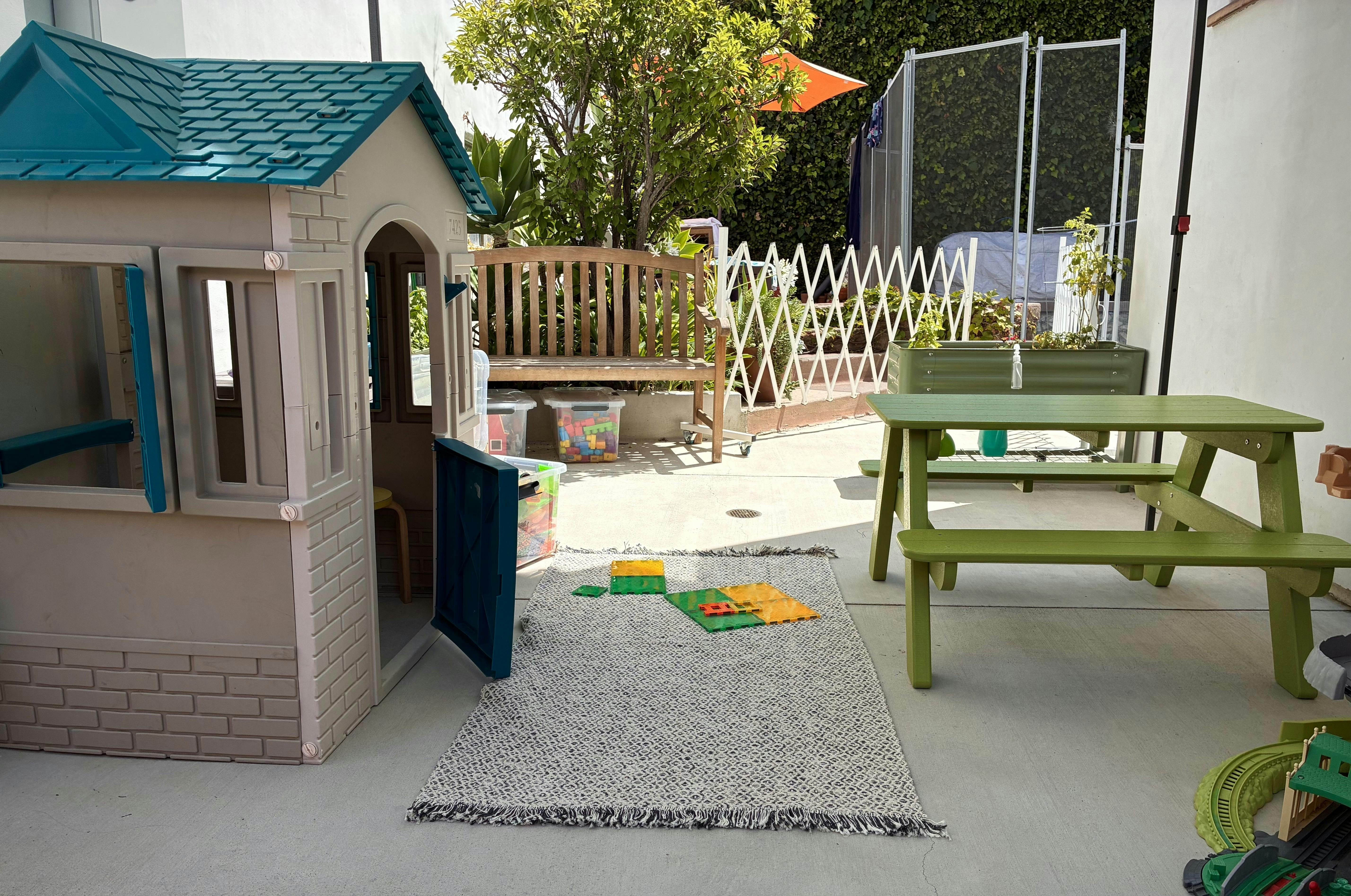 Plastic playhouse and small picnic table in a patio play area
