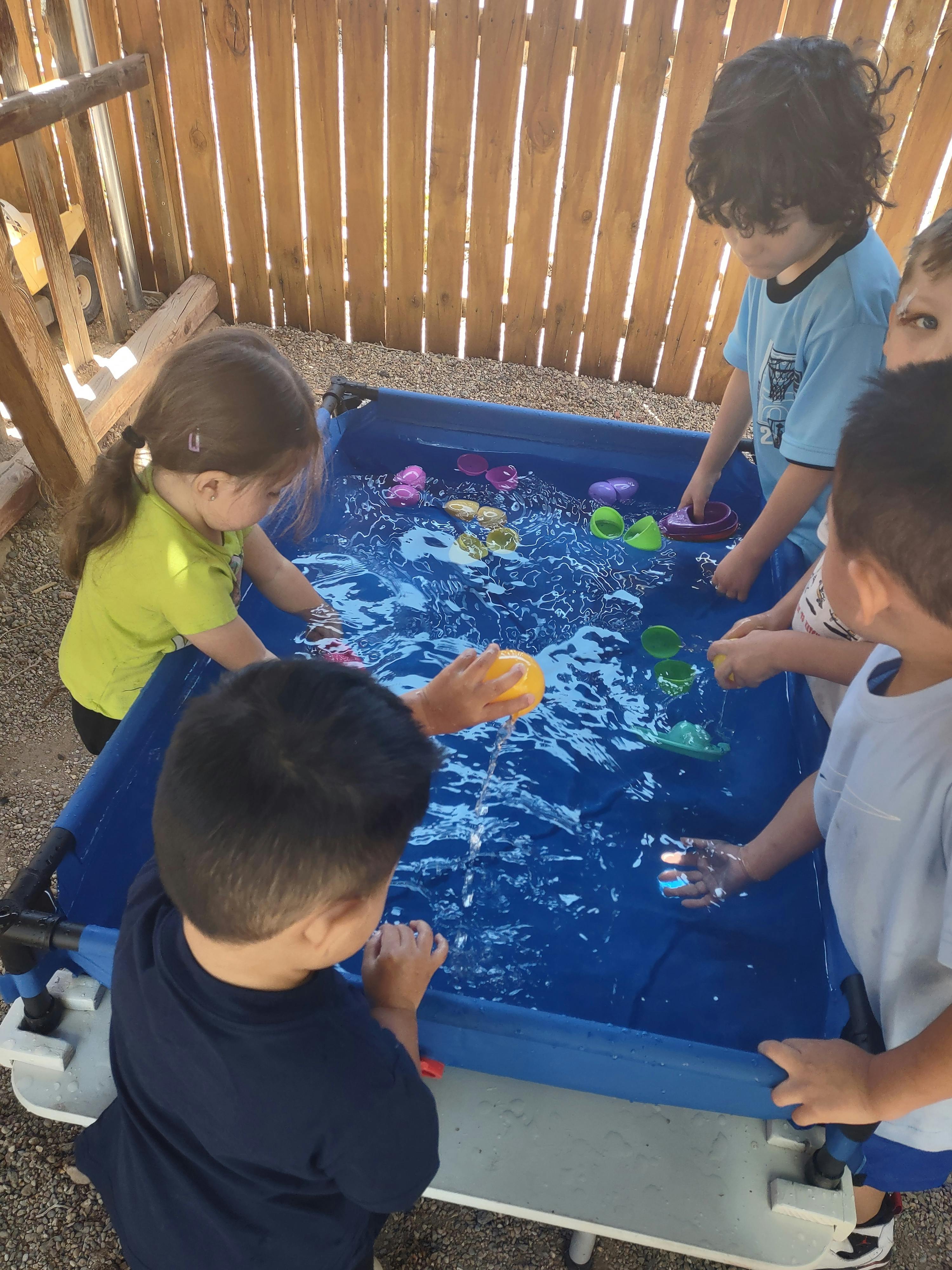 Children playing with small plastic toys in a water table