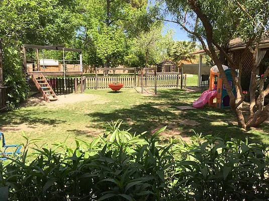 Backyard with a wooden playset, swing, and small plastic slide