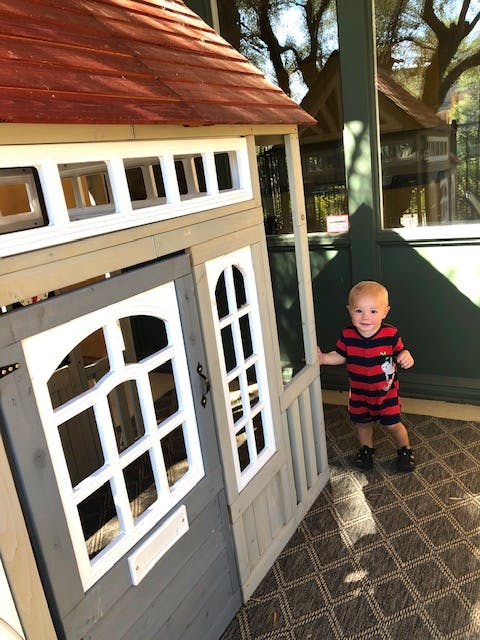 Child standing next to a playhouse