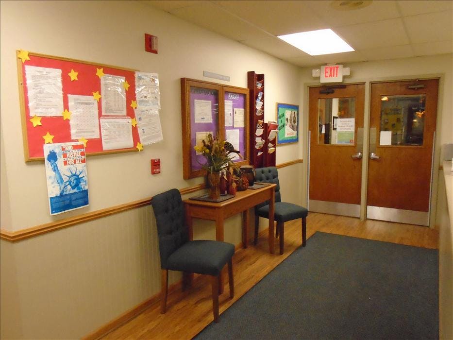 Hallway with bulletin boards, small table with two chairs, and two wooden doors