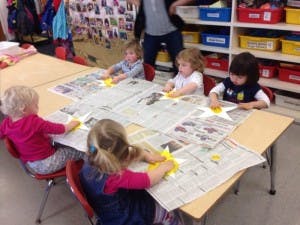 Children doing an art project with newspaper at a table
