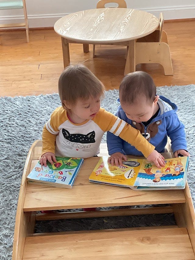 Two children looking at books on a wooden shelf