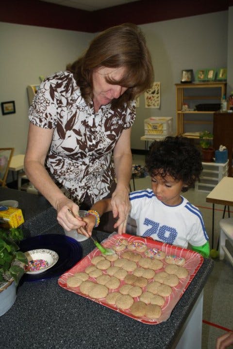 Adult and child decorating cookies on a tray