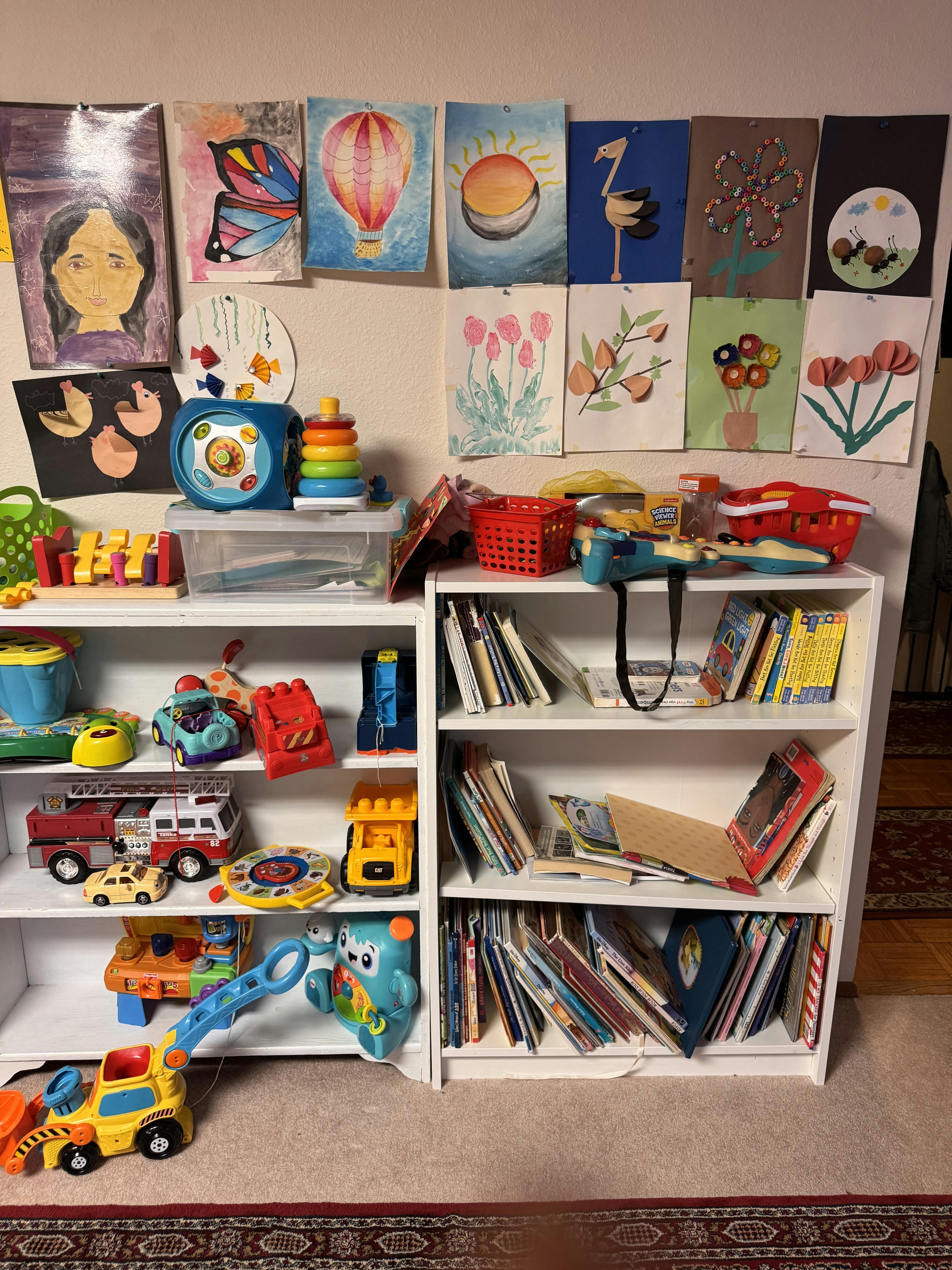 Children's bookshelves filled with assorted toys and books under wall art