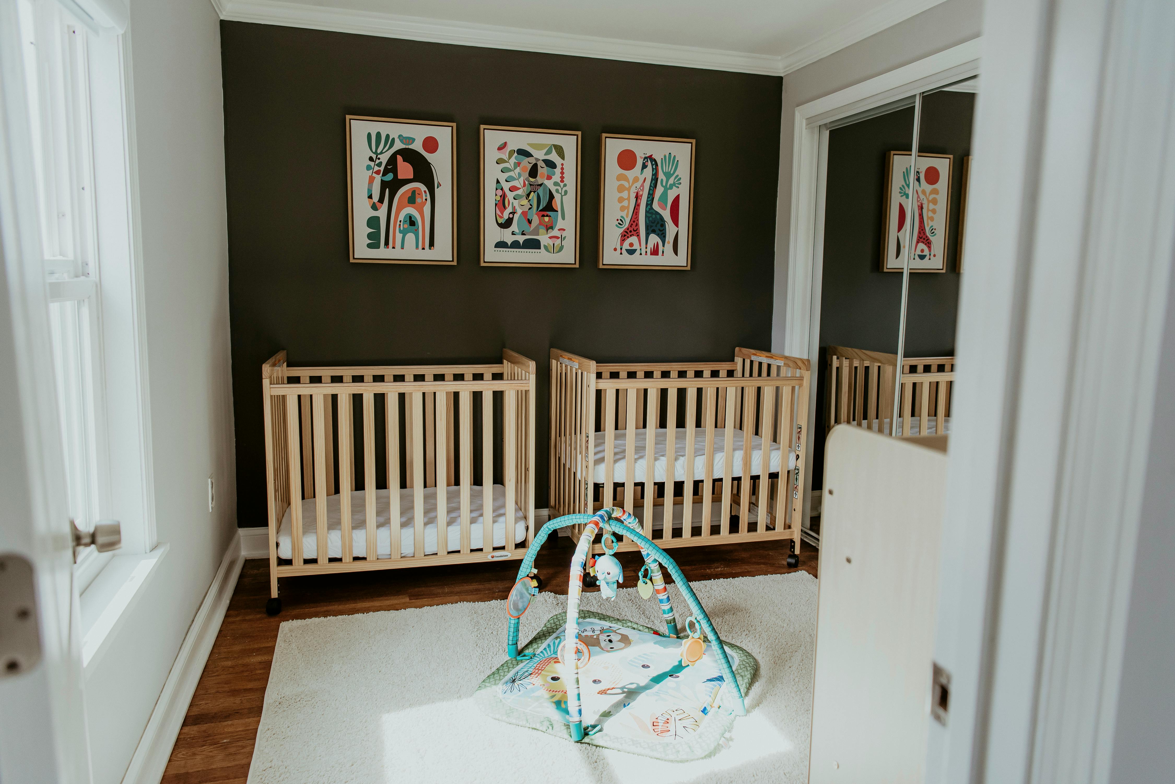 Two cribs and a baby play mat in a nursery