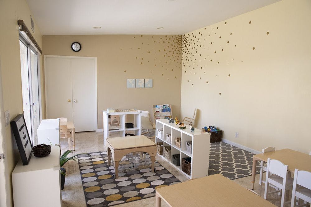 Classroom with small tables, chairs, and storage shelves