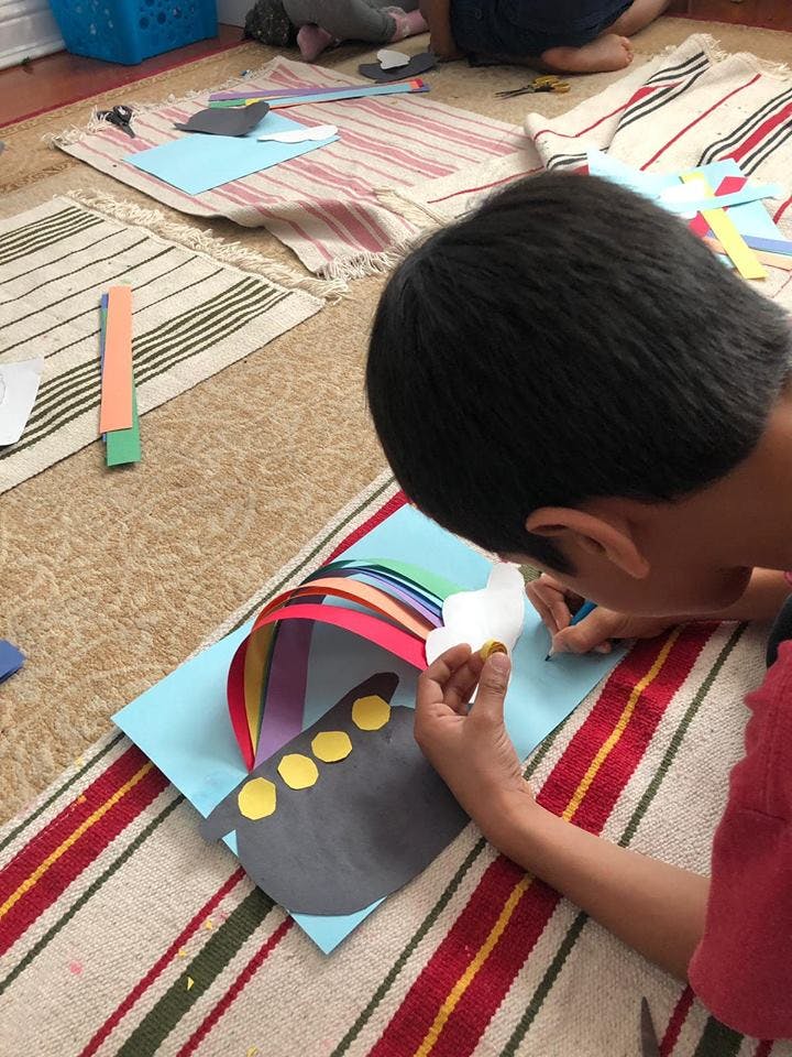Child making a paper craft with colorful strips