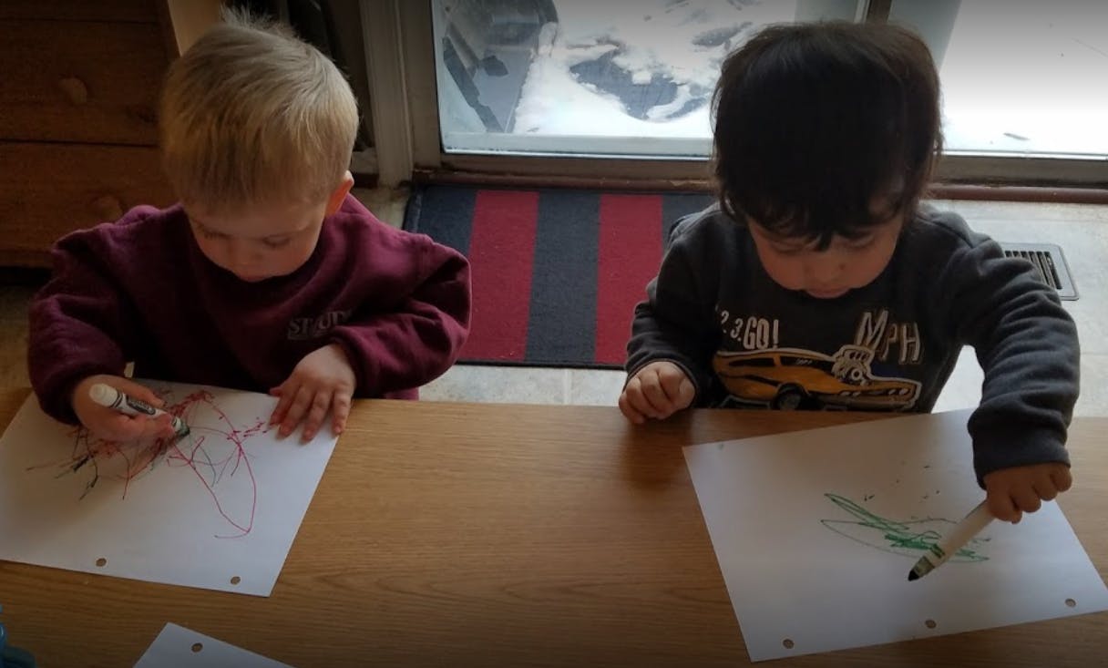 Two children drawing at a table